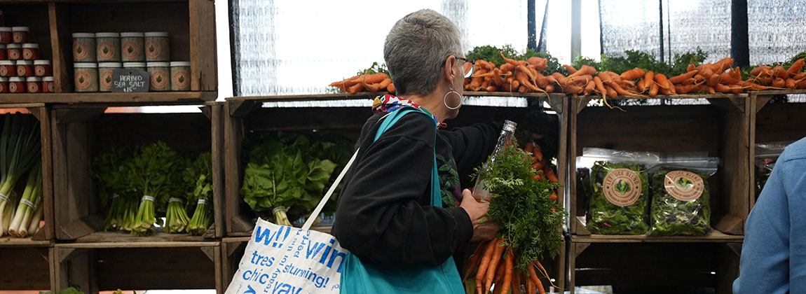 A woman grabbing vegetables from a table inside